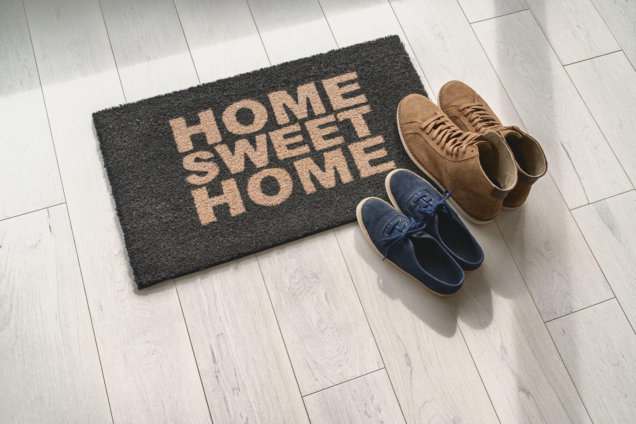 Home sweet home doormat with brown and blue shoes beside it, symbolizing comfort and security in a home, relevant to homeowners insurance in Osceola, WI.