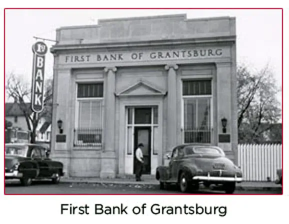 Historic First Bank of Grantsburg building, featuring a classic facade, sign reading "FIRST BANK OF GRANTSBURG," and a vintage car parked in front, representing the agency's origins in 1945.