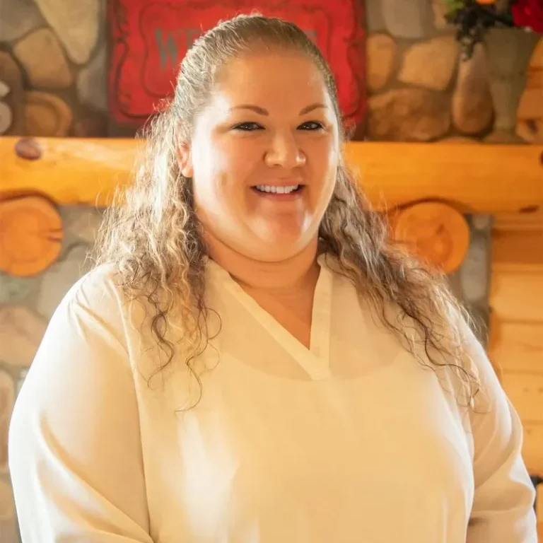 Liz Shultz, Agency Manager and Personal Lines Agent at Jensen-Sundquist Insurance Agency, smiling in a cozy office setting with wooden accents.