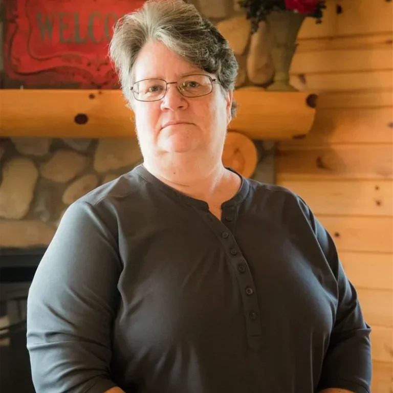 Peggy Moore, Personal Lines Agent at Jensen-Sundquist Insurance Agency, standing in an office setting with wooden decor.