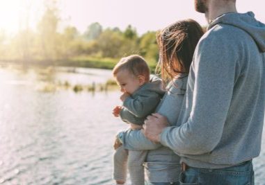 Happy family with Cute baby boy on lake water background outdoors, sensitivity to the nature concept