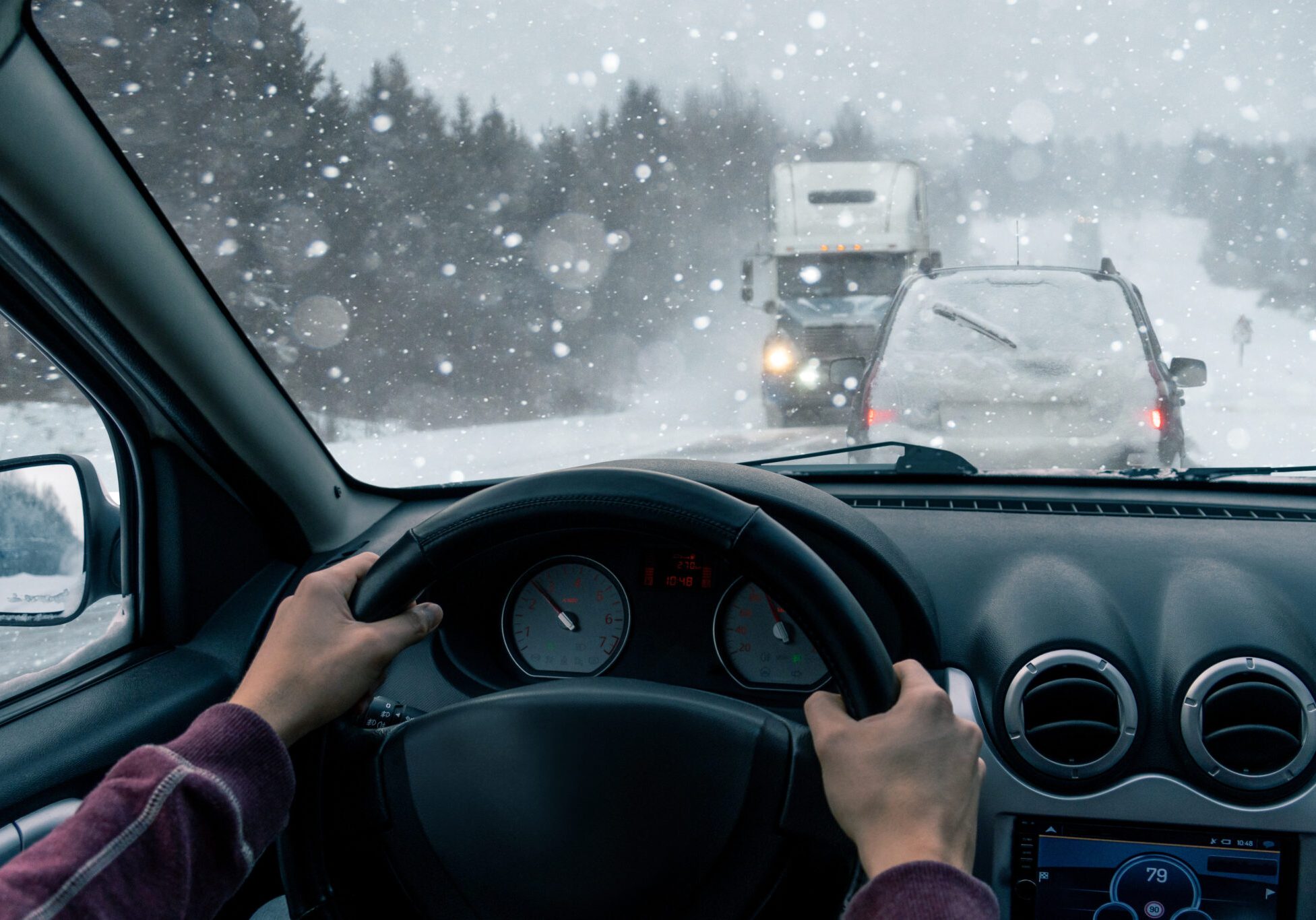 A man drives a car on a winter road in a blizzard