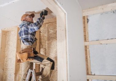 General Construction Contractor Attaching Drywall Using Cordless Drill Driver. Caucasian Remodeling Worker in His 40s.